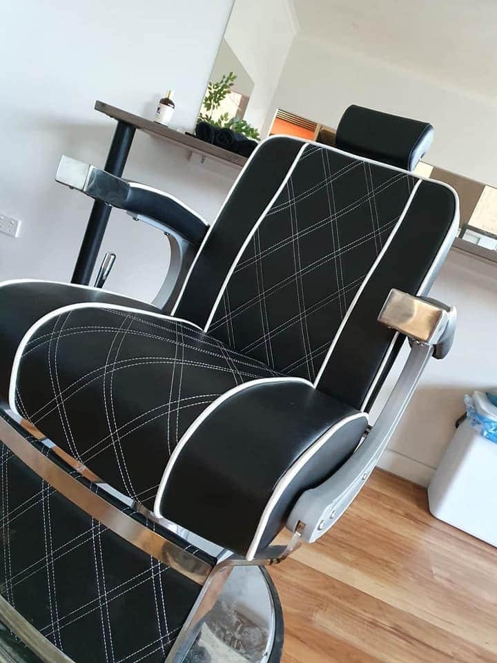 Black diamond-stitched barber chair inside Colossal Barbers